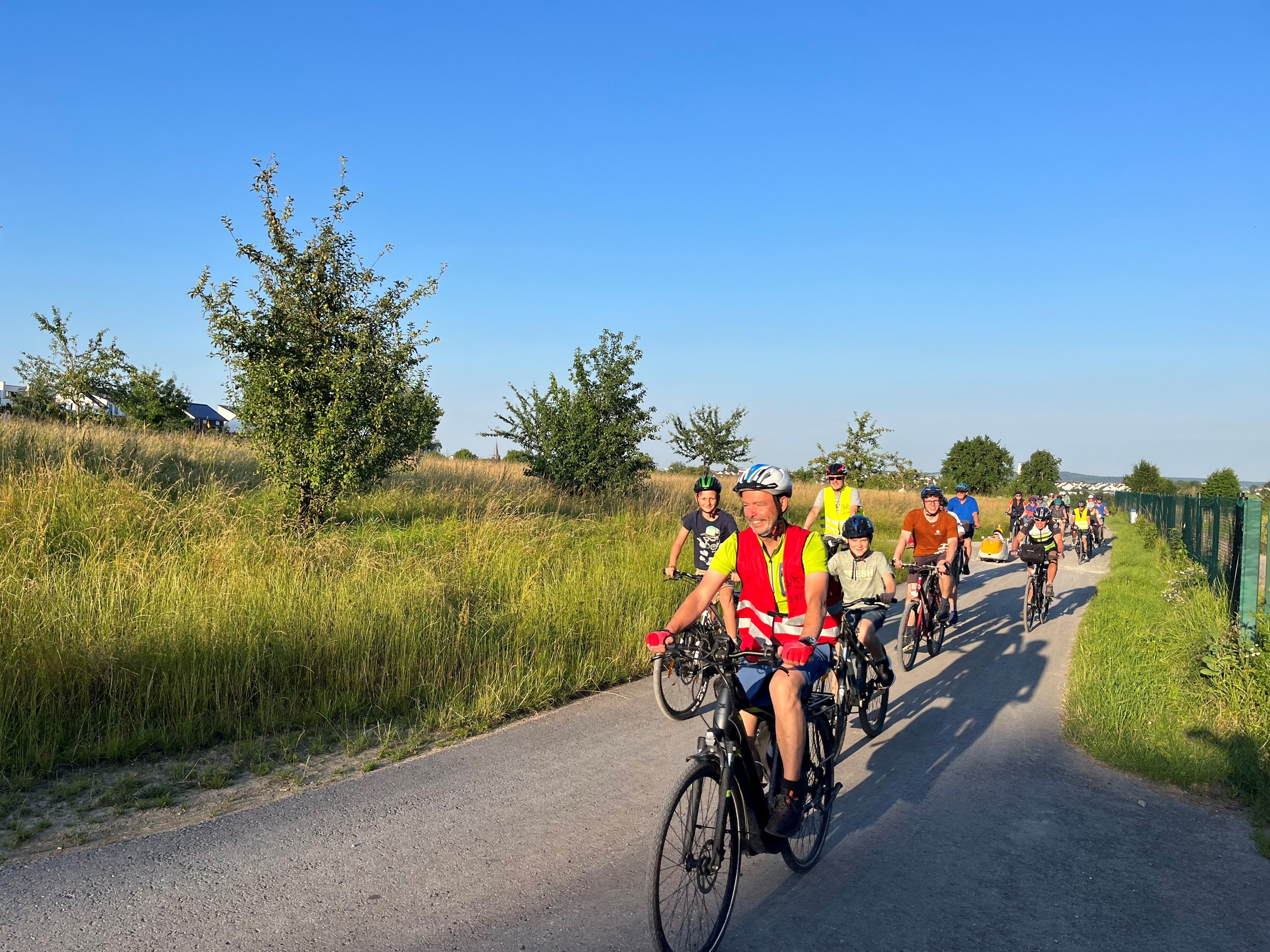 Eine Gruppe Radfahrer radeln auf einem geteerten Weg zwischen den Rutesheimer Feldern.